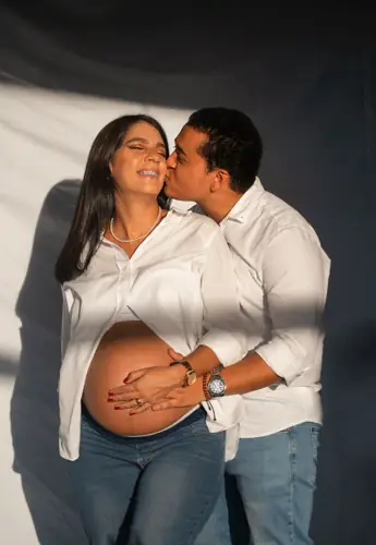 Sesión de maternidad en pareja: él la besa en la mejilla