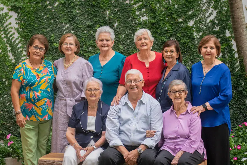 Foto familiar de abuelos y familia frente a un muro de hojas