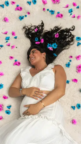 Mujer embarazada recostada entre flores rosadas y azules