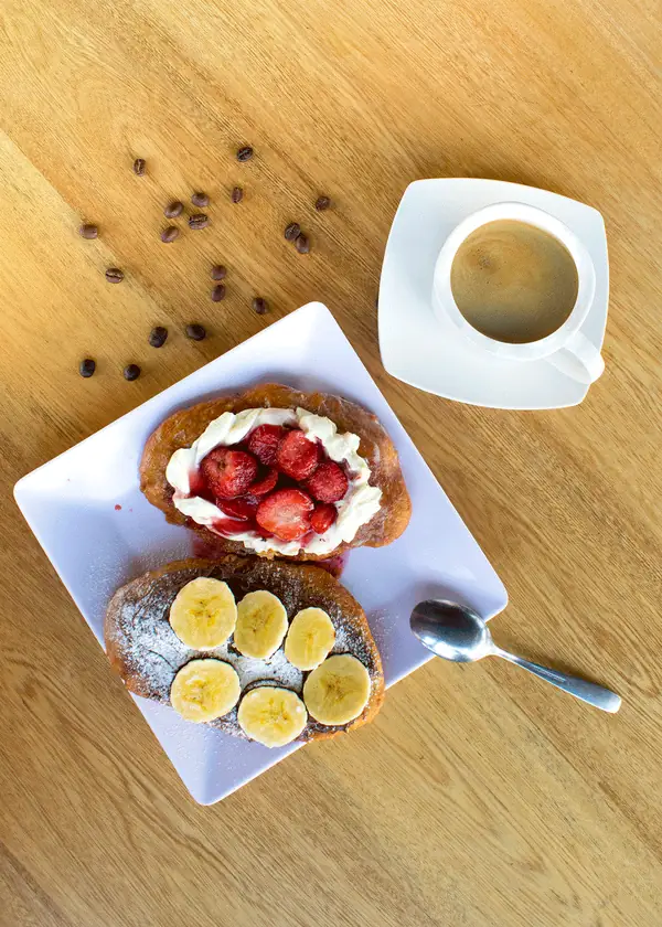 Waffle con fresas y banano acompañado de café