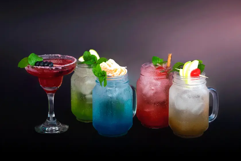 Cócteles y bebidas de colores sobre fondo oscuro